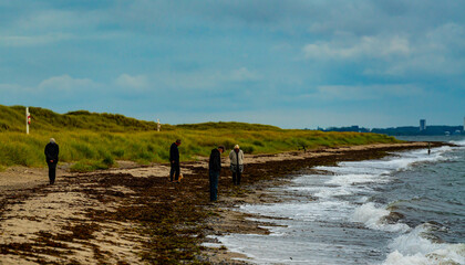 People walking along a beach in the Baltic region on a stormy autumns day.