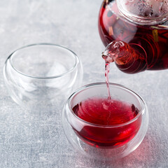 red tea is poured from a teapot into a bowl