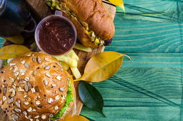 juicy Burger with meat and hot dog with sausage in yellow and green leaves close up	
