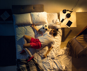 Champion. Top view of young professional football, soccer player sleeping at his bedroom in...