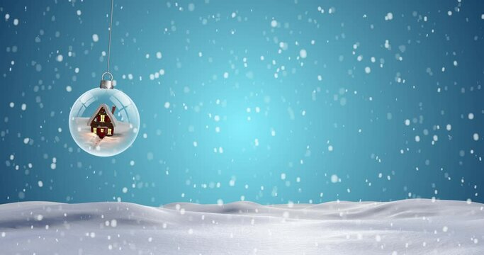 Christmas bauble dangling against snowflakes falling on blue background