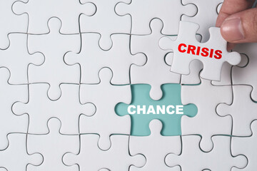 Chance and Crisis concept , Hand pull out white jigsaw which print screen crisis wording to show chance wording on blue background.