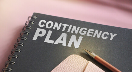 Contingency Plan words on upper page of copybook, pen and pink leather wallet. business crisis concept