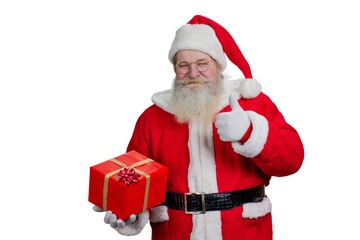 Santa Claus giving thumb up sign. Portrait of realistic Santa Claus with red gift box standing on white background and giving thumb up. Studio shot of man in costume of Santa Claus.