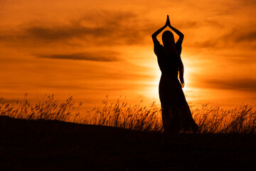 Silhouette of a woman enjoys meditate  at beautiful sunset.