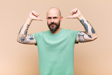 young bald and bearded man feeling proud, arrogant and confident, looking satisfied and successful,...