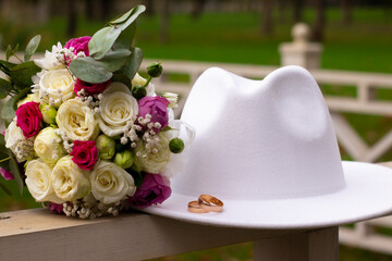 wedding rings on a white stylish hat next to the bride's bouquet. marriage concept.