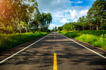 Empty asphalt road through the green field and clouds on blue sky in summer day. 
