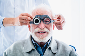 Oculist putting ophthalmic glasses on smiling elderly male patient - obrazy, fototapety, plakaty