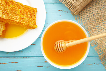 Bowl of honey with honeycomb on blue wooden table