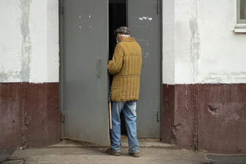 Obraz na płótnie Canvas An elderly man enters the house. Grandpa is walking home from the street.