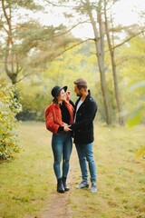 Young couple in love walking in the autumn park holding hands looking in the sunset