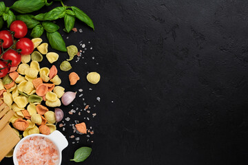 Italian Pasta orecchiette with traditional ingredients for the preparation food on black background. Culinary food cooking background. Top view.