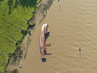 Vista desde un dron de un barco oxidado, parcialmente hundido, desde el que solo se puede ver el...