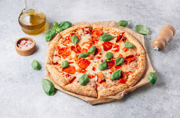 Pepperoni pizza with basil on a rustic background.