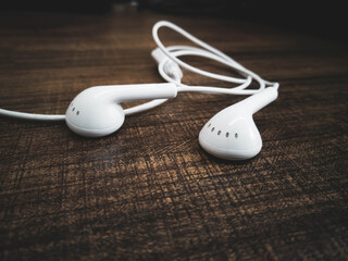 White earphone on wood texture background.