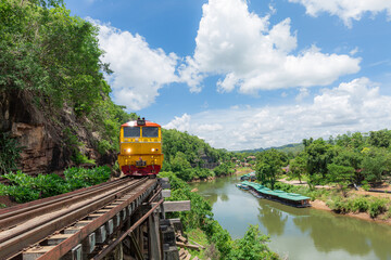 Naklejka premium World war II historic railway, known as the Death Railway with a lot of tourists on the train taking photos of beautiful views over Kwai Noi River.