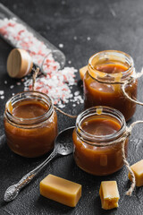 Homemade salted caramel sauce in jars and caramel candies