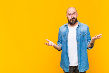 young bald and bearded man feeling clueless and confused, not sure which choice or option to pick,...