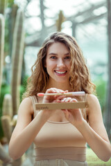 Pretty young woman in beige clothes showing a toothbrush and looking good