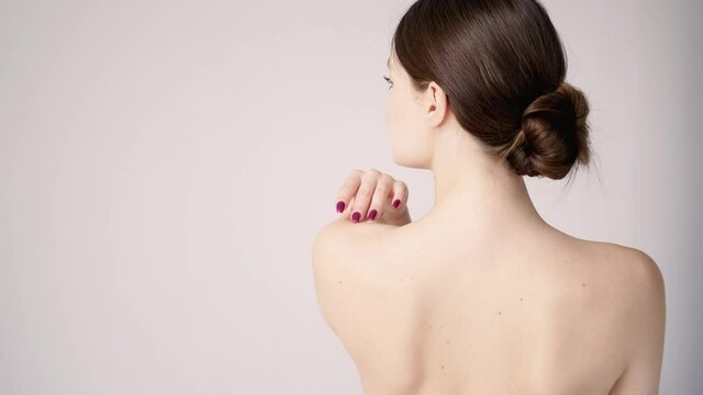 Female naked shoulders close-up. View from the back. Young sexy woman touching body