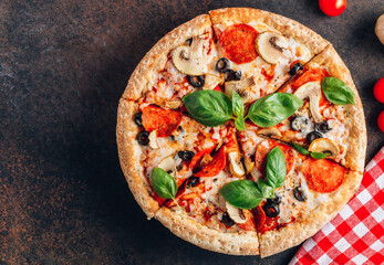 Sliced italian pizza with salami, mozzarella, mushroom, tomatoes, black olives and basil leaves on black background. Italian traditional food. Popular street food concept