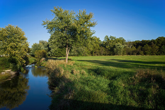 Farmland stream and pasture having undergone streambank restoration and stabilization on a warm sunny autumn day.