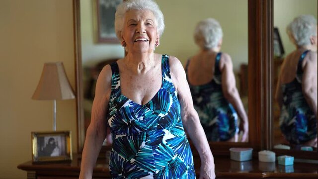Elderly woman smiling and laughing while modeling a bathing suit she wears in water aerobics classes. Concept of active senior female having fun in retirement.