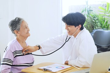 Young doctor examining elderly woman in hospital.