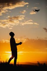 Fototapeta premium Silhouette of a man piloting a drone on A Rural Setting during sunset