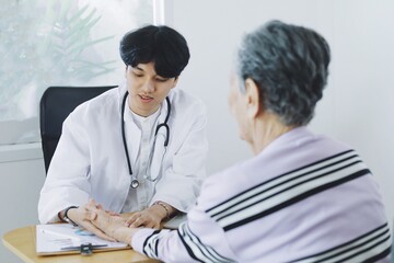 Young doctor examining elderly woman in hospital.