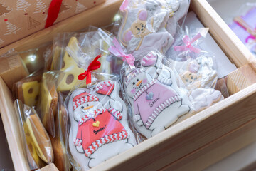 A cute Christmas gingerbread in the form of a snowman in a pink sweater lies in a box with other sweets, a gingerbread in the form of a piece of cheese