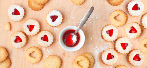 Top panoramic view of Christmas Linzer cookies filled with strawberry jam on wooden board.