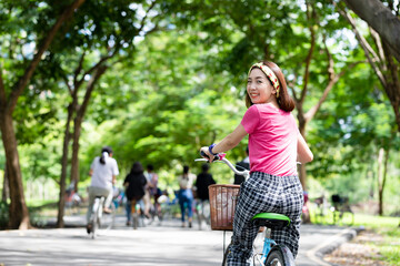 Happy beautiful woman riding bicycles outside enjoy summer sport in the public park. Relax and healthy freedom concept. Sports concept