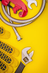 Plumbing tool and gloves for connecting water hoses on a yellow table for work. Working environment of master plumber