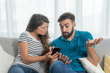 Young couple arguing about text messages on the boyfriends phone where girlfriend is jealous for finding the communication with other girl