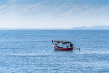 Lonely fishing boat in the sea and the coast on the horizon in Thailand