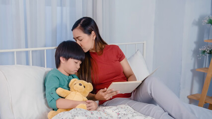 Mom is telling fairy-tale stories to her children before sleep on bed.