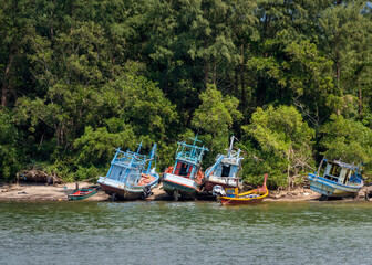 Abandoned fishing boats on the sandy beach near the rainforest