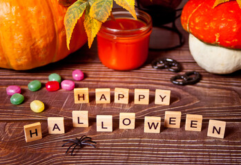 Happy Halloween wooden blocks text, pumpkins, candle, candies on the background