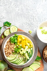 Burrito bowl with quinoa and green vegetables. Quinoa, cucumber, pepper, radish and celery in a bowl on a gray background top view. Free space for text. Healthy diet food, vegetarian food. Copy space