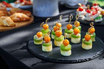 Outdoor catering banquet in summer. Table with canapes and fruits at a summer banquet