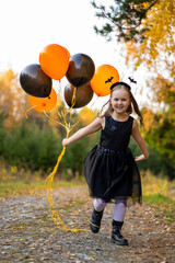 Happy Halloween, a girl in the autumn forest with balloons laughs