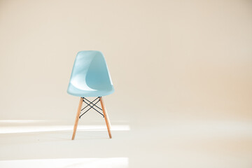 One blue chair in a light white Studio lit by sunlight in a minimalistic style with a copy of the space, selective focus