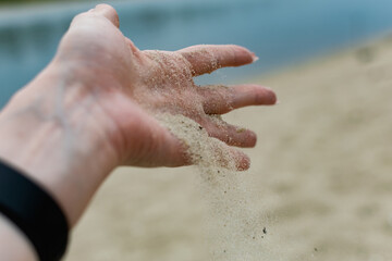 River shells and fine white river sand fall from a woman's hand in nature