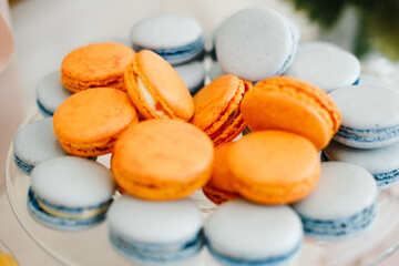 Blue and orange macarons lie on a glass stand, macro