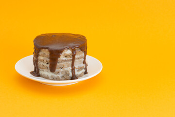 Chocolate cake with streams on a plate. Halloween concept, trick or treat. Handmade cooking, sweets with flows down. Brownies with cream. Orange background, copy space for text. Selective focus, blur.