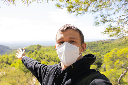 Chico adolescente con mascarilla FFP2 haci&eacute;ndose un selfie en la monta&ntilde;a