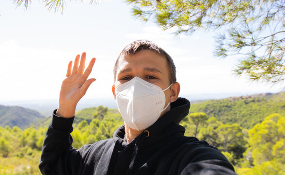 Chico adolescente con mascarilla FFP2 haci&eacute;ndose una foto en la monta&ntilde;a