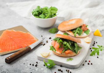 Fresh sandwiches with bagel and salmon, cream cheese and wild rocket on white board with smoked...